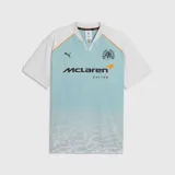 Camiseta deportiva PUMA de McLaren Racing, con diseño en celeste y blanco, cuello en V y detalles en naranja. Presenta el logo de PUMA, el emblema de la escudería y el patrocinio principal en el frente.
