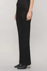 Pantalón sastrero negro con lúrex, de calce slim, botamanga flare y bolsillos ojal en la espalda. Presenta cierre frontal con broche personalizado y botón auxiliar interno.