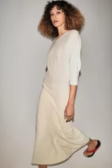 Vestido midi de punto color marfil con escote en V, mangas largas de sisa ancha, cintura entallada y falda de corte evasé.