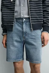 Bermuda de jean con corte regular fit, confeccionada en denim de algodón con elasticidad. Presenta diseño de cinco bolsillos, efecto lavado y cierre frontal con cremallera y botón.