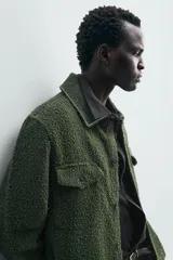 Sobrecamisa de hombre relaxed fit color verde oscuro, confeccionada en tejido de textura efecto toalla. Cuenta con cuello solapa, manga larga con puño abotonado, bolsillos de parche con solapa en el pecho, pespuntes a contraste y cierre frontal con botones.