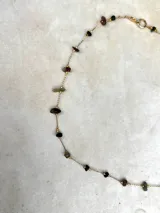 Collar delicado de cadena dorada con pequeñas piedras naturales en tonos variados, dispuestas de forma sutil a lo largo de la pieza.