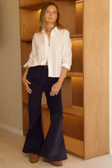 Pantalón de corderoy color beige, tiro alto, corte ajustado en muslos y campana marcada en la parte inferior.