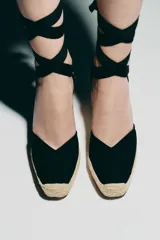 Zapato destalonado con tacón tipo cuña, color negro, con combinación de materiales en el corte y tiras para atar en el tobillo.