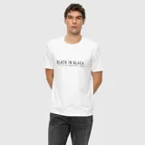 Remera blanca de corte regular con cuello redondo y mangas cortas. Presenta un estampado frontal con la frase 'BLACK IN BLACK' en color negro.