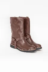 Bota de caña alta de cuero marrón, con diseño urbano y líneas limpias. Cuenta con una correa decorativa en el tobillo con argolla metálica y remaches plateados, suela de goma con costura reforzada y tirador trasero superior.