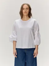 Remera blanca con cuerpo de algodón liso y mangas abullonadas semitransparentes con textura de lunares.