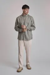 Camisa de lino verde oliva de corte clásico, con cuello abotonado y mangas largas.