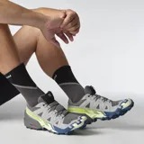 Championes Salomon Speedcross 6 de color negro, diseñados específicamente para trail running. Presentan una estructura robusta y técnica, capellada sintética y textil con refuerzos termosellados, sistema de cordones de ajuste rápido Quicklace y suela con tacos profundos para máxima tracción en terrenos difíciles.