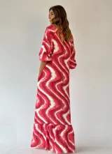 Vestido largo camisero de algodón, con estampado tipo tie-dye en tonos fucsia y blanco, cierre frontal con botones, cuello camisero y mangas largas.