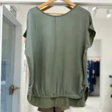Blusa verde seco de corte holgado, con cuello redondo, mangas cortas y dobladillo inferior curvado.