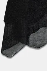 Falda corta negra con efecto metalizado o brillante, cintura elástica y bajo asimétrico con capas superpuestas de tejido ligero.