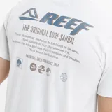 Remera de corte regular fit color blanco, con cuello redondo y manga corta. Presenta un estampado vertical pequeño en el lado izquierdo del pecho con el logo de la marca y elementos gráficos circulares.