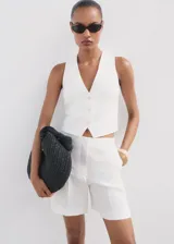 Short de lino color blanco, de tiro medio y diseño recto con bolsillos laterales.