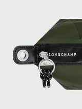 Cartera de mano modelo Le Pliage Energy en tamaño S, color verde oliva. Presenta solapa y asas de cuero negro, cierre principal con broche a presión y correa ajustable extraíble con detalles en blanco y negro.