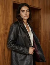 Blazer de cuero vacuno en color negro con efecto gastado y costuras a la vista. Presenta solapas clásicas, cierre frontal con dos botones y bolsillos laterales con solapa.
