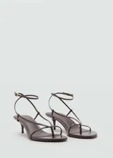 Sandalia de tacón bajo tipo kitten heel, con diseño de tiras finas que envuelven el pie y cierre de pulsera al tobillo con hebilla metálica. Presenta punta redonda y acabado liso.
