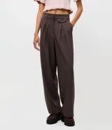Pantalón de sastrería corte recto color marrón, con pliegues frontales, cintura con trabillas y bolsillos laterales.