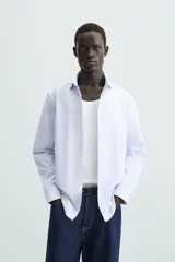 Camisa de algodón de manga larga, color celeste claro, con cuello italiano y cierre frontal de botonadura.