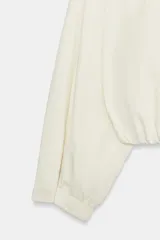 Chaqueta de nylon color crudo, con cuello alto, mangas largas, bolsillos delanteros, bajo abullonado con elástico y cierre frontal con botones forrados.