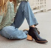 Botineta de cuero negro con diseño de punta fina y puntera texturizada efecto cocodrilo. Presenta una suela con borde en tono natural y cierre lateral.