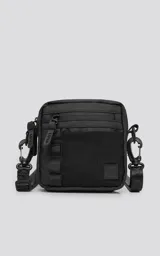 Mini bolso negro de estilo modular, confeccionado en tejido tracker impermeable. Presenta tres compartimentos con cierre y correa ajustable para llevar al hombro o cruzado.