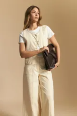 Chaleco negro de vestir con cuello solapa y cierre frontal de botones. Presenta costuras contrastantes blancas que definen el diseño y bolsillos delanteros. Se combina con una camisa blanca de manga larga.