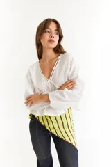 Blusa blanca de algodón con diseño de escote en V, mangas largas abullonadas y detalle de frunces en el frente y la espalda.