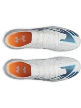 Championes de fútbol Under Armour Shadow Elite 4 Mach FG, color blanco con detalles en azul y naranja, diseñados para césped natural con placa de fibra de carbono y tacos especializados para máxima velocidad y agilidad.