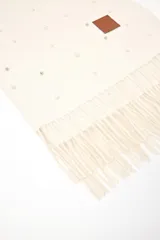 Pashmina de tejido de punto color blanco, decorada con pequeñas perlas dispersas por toda la superficie. Presenta flecos en los extremos y una etiqueta de cuero sintético con logo en una esquina.