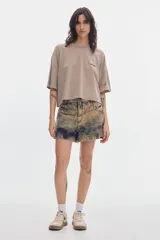 Short de denim tiro alto y corte relajado, con efecto de lavado desgastado en tonos amarillos y oscuros, pierna ancha y costuras en la parte delantera.