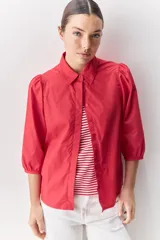Camisa blanca de algodón, de calce relajado, con cuello camisero, frente abotonado y mangas largas abullonadas.