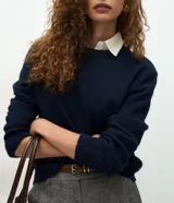 Suéter de punto gris con cuello redondo y diseño de cuello camisero celeste superpuesto. Presenta mangas largas y terminaciones acanaladas en puños y cintura.