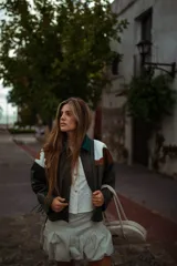 Campera de cuero de silueta oversize y corte corto, con cuello camisero verde oscuro, detalles en pelo de vaca marrón y blanco, y mangas amplias.