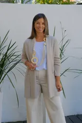 Saco tipo cárdigan abierto de corte recto y largo medio, color visón, con mangas largas y bolsillos frontales aplicados.