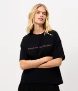Remera de algodón color negro con cuello redondo y mangas cortas. Presenta un estampado frontal con el logo de la serie House of the Dragon en color rosado.