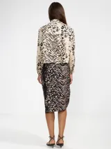 Camisa de lino 100% italiano, de corte cropped y silueta fluida, con cuello clásico y cierre frontal de botones. Cuenta con estampa animal print que combina patrones de leopardo y cebra en tonos beige, crema y negro, y detalle de botón en forma de flor en el cuello.