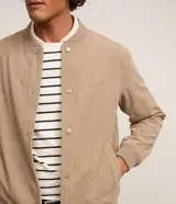 Campera bomber masculina de terciopelo cotelé color beige, con cuello redondo, mangas largas, cierre frontal de botones forrados, bolsillos laterales y terminaciones de elástico en puños y cintura.