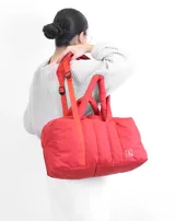 Bolso tipo tote color beige con diseño acolchado y doble asa de hombro.