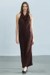 Vestido midi de tejido satinado en color marrón oscuro, con cuello halter de escote fluido, hombros descubiertos y cierre posterior con botones.