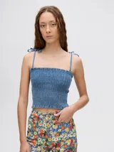 Top crop de tela denim con efecto fruncido, breteles finos ajustables con lazos y diseño entallado al cuerpo.