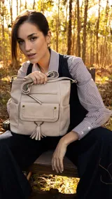 Bandolera negra de cuero sintético con cierre superior y correa larga regulable. Tiene bolsillo frontal con tapa y broches magnéticos, detalle de trenza artesanal, división interna, bolsillos internos y bolsillos laterales tipo ojal.