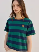 Remera de corte clásico a rayas horizontales en tonos verde y azul marino, con cuello redondo marrón y logo bordado en el pecho.