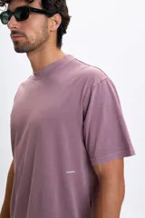 Remera de manga corta con corte oversize, color violeta con efecto lavado. Presenta una estampa gráfica en la espalda que ilustra un disco de vinilo sobre una bandeja giradiscos con texto decorativo.