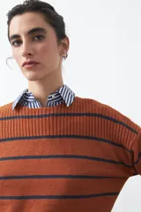 Sweater de tejido de punto con diseño de rayas horizontales en tonos bordó y rojo. Presenta cuello redondo, mangas largas con hombros caídos y terminaciones acanaladas en puños, cuello y ruedo.