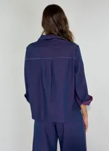 Chaqueta tipo camisa de denim color borgoña, con cuello clásico, manga larga, cierre frontal con botones y bolsillo de parche en el pecho.