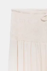 Falda larga color crudo, de tiro alto con cintura elástica tipo nido de abeja y cordón ajustable.