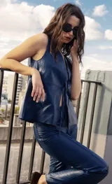 Chaleco de cuero ovino en color azul, con escote en V y cierre frontal mediante lazadas de cuero. Presenta un diseño sin mangas, de calce amplio y liviano, sin forro interior.