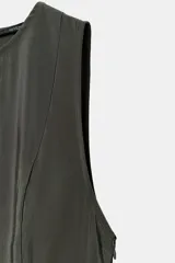 Vestido midi color verde oscuro, confeccionado en tejido fluido. Presenta cuello redondo, manga sisa y bajo con línea evasé y pliegues. Tiene cierre lateral con cremallera oculta y cierre en la espalda con abertura y botón.