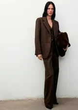 Blazer de corte recto confeccionado en tejido mezcla de lana con diseño jaspeado. Presenta cuello con solapas de muesca, cierre frontal con botones, dos bolsillos de parche delanteros, mangas largas con puños abotonados y abertura posterior en el bajo. Incluye forro interior.